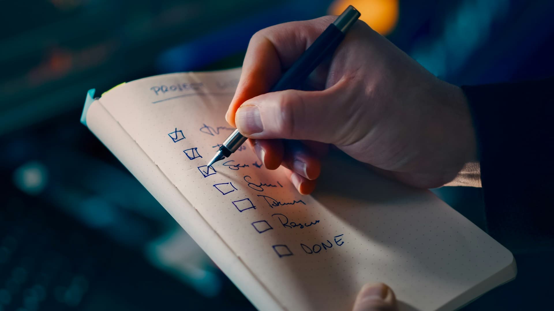 Main cochant les éléments d'une checklist sur un carnet, préparation à une échéance.