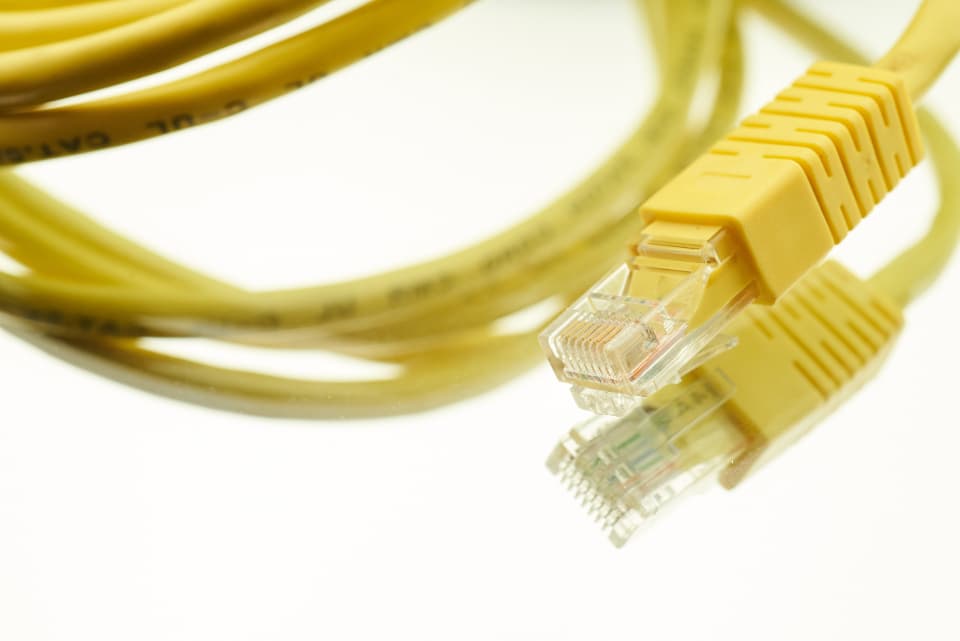 Câbles réseau Ethernet jaunes enroulés, illustrant des connexions.