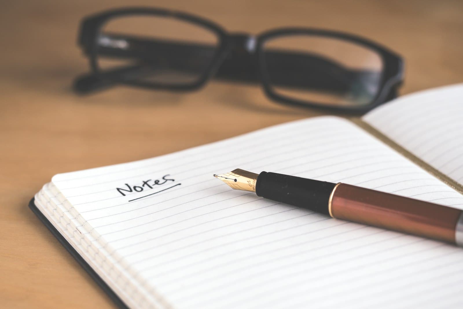 Carnet ouvert avec un stylo plume et une paire de lunettes, prise de notes.