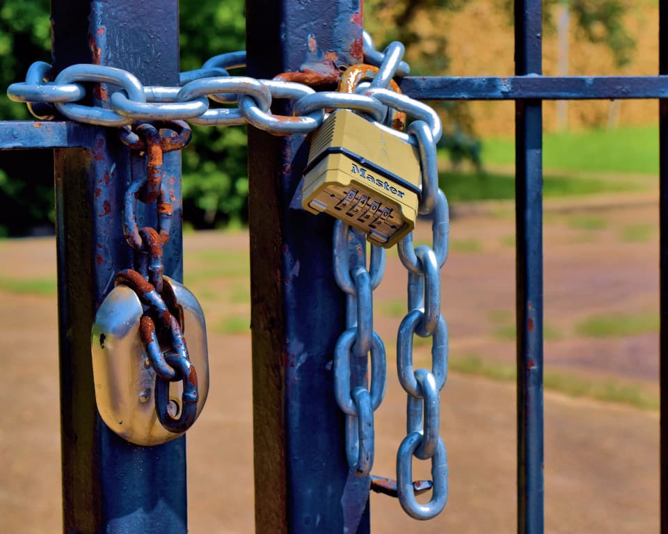 Cadenas à combinaison et chaîne fermant un portail métallique.
