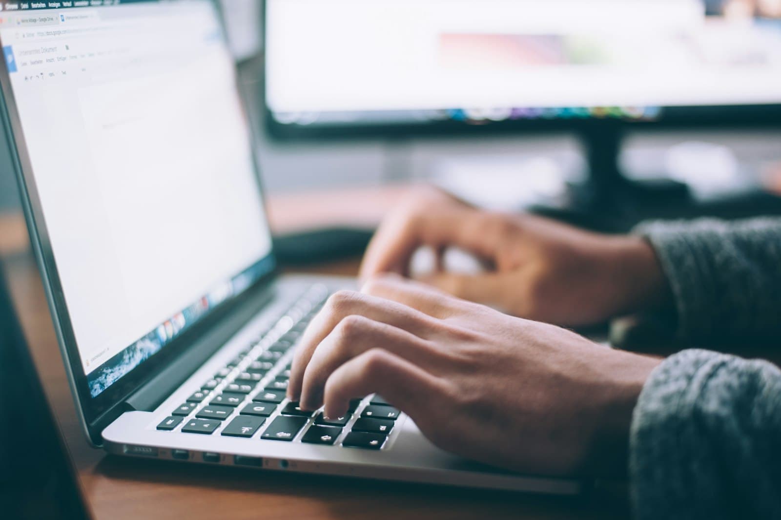 Personne rédigeant un email sur un ordinateur portable dans un bureau lumineux.