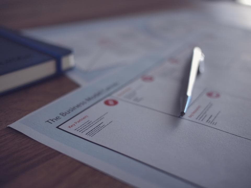 Document de travail et stylo posés sur un bureau en bois.