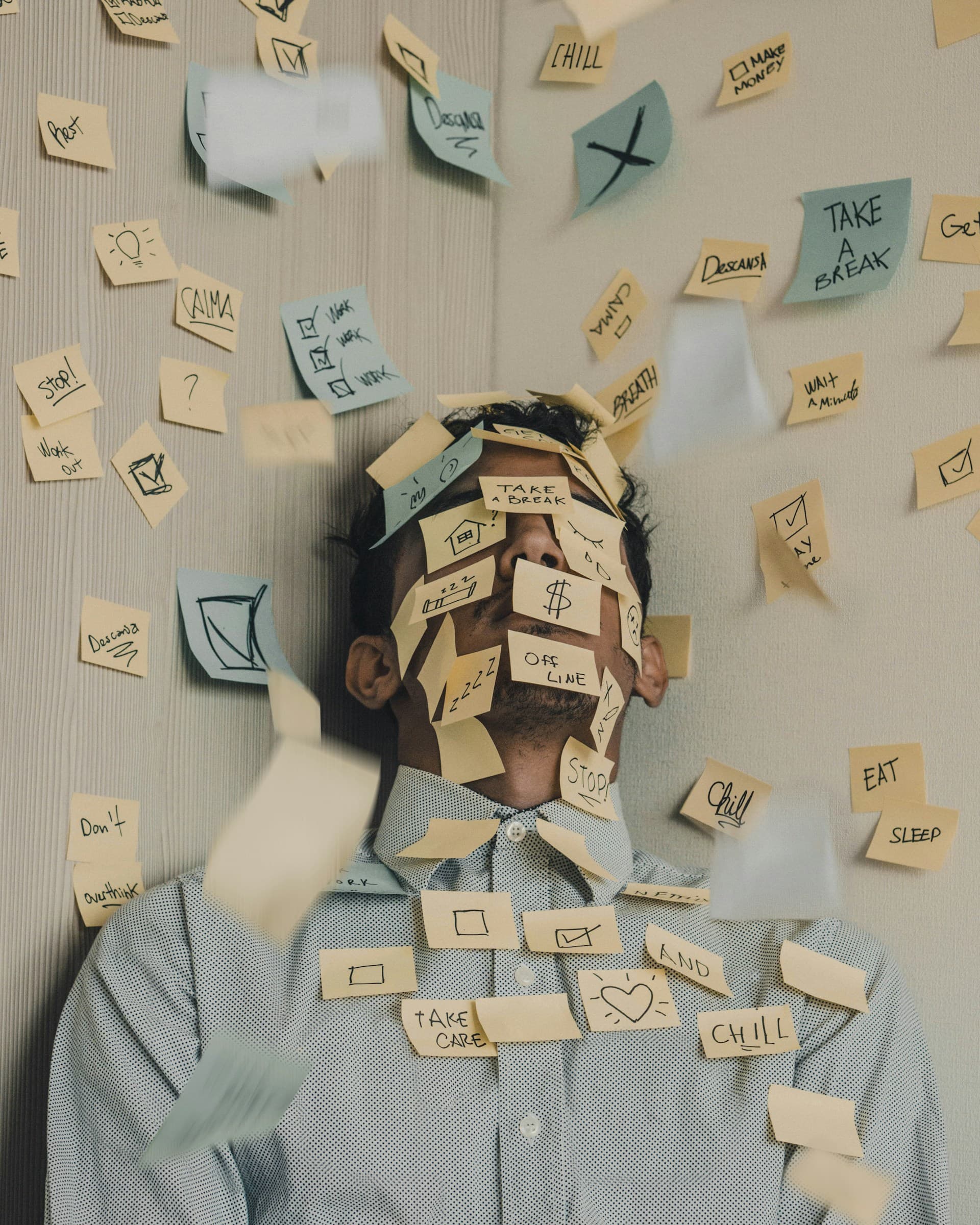 Professionnel stressé devant une pile de documents administratifs sur son bureau.